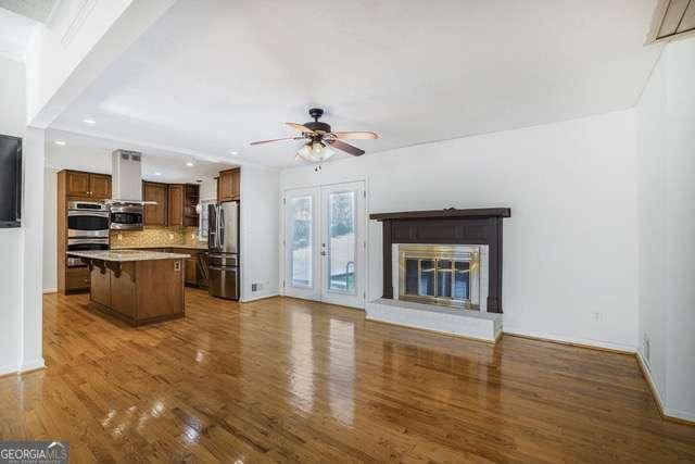 living area featuring a ceiling fan, a glass covered fireplace, dark wood-type flooring, baseboards, and recessed lighting