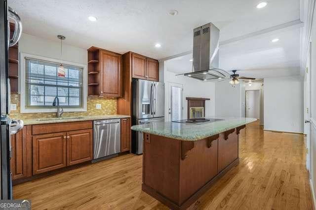 kitchen featuring open shelves, stainless steel appliances, island exhaust hood, a sink, and ceiling fan