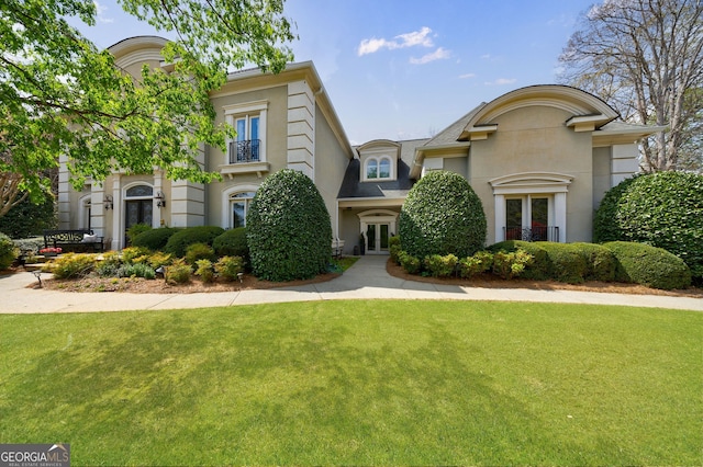 view of front facade with a front lawn, stucco siding, and french doors