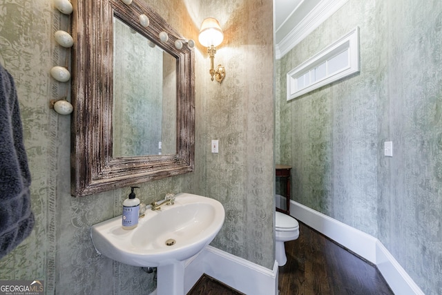 bathroom featuring baseboards, wood finished floors, and toilet