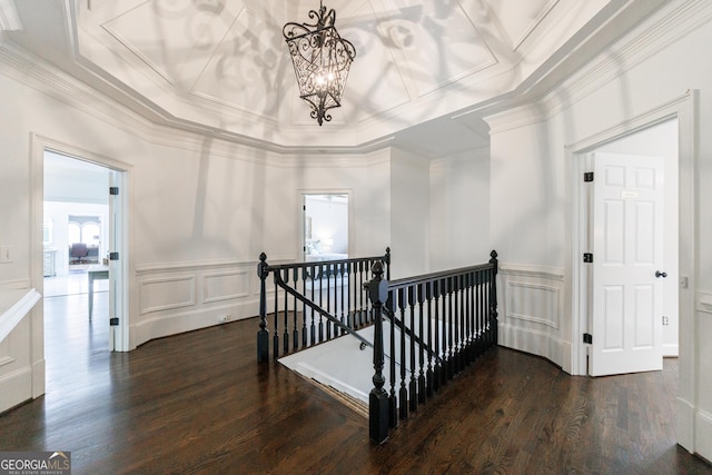 stairway featuring crown molding, coffered ceiling, a decorative wall, and a chandelier