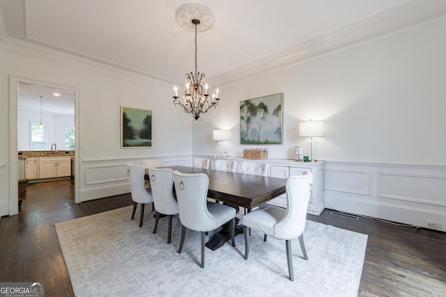 dining space featuring visible vents, crown molding, an inviting chandelier, a decorative wall, and dark wood-type flooring