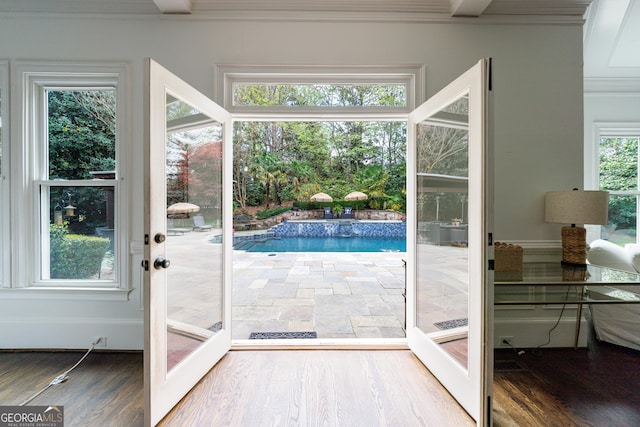 doorway with ornamental molding and wood finished floors