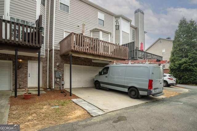 back of property with driveway, a garage, and brick siding