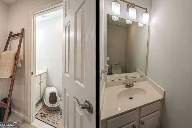 bathroom with toilet, vanity, and tile patterned floors