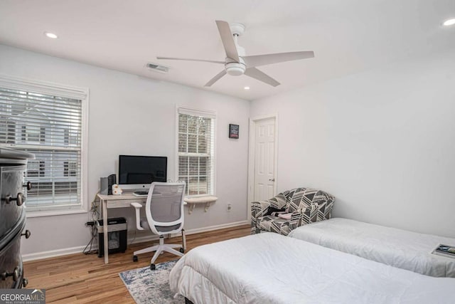 bedroom featuring baseboards, visible vents, multiple windows, and wood finished floors