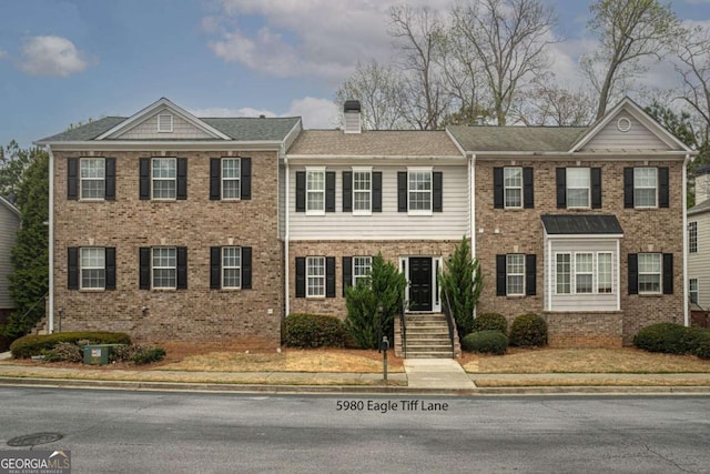 view of front of home with a chimney and brick siding
