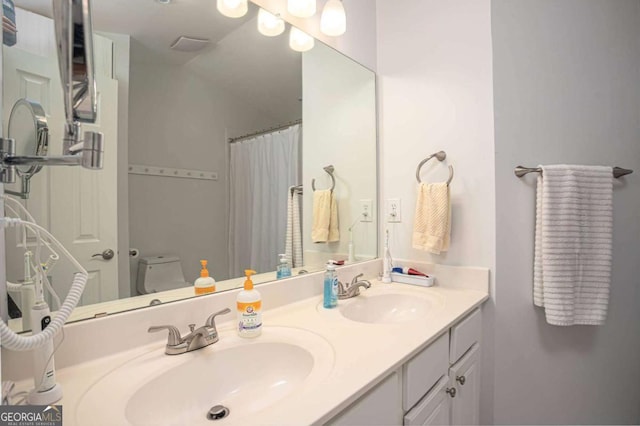 bathroom with double vanity, a sink, curtained shower, and toilet