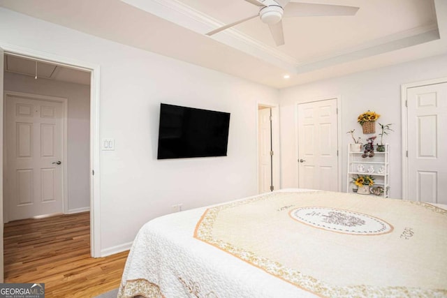 bedroom featuring a raised ceiling, baseboards, attic access, and light wood-style flooring