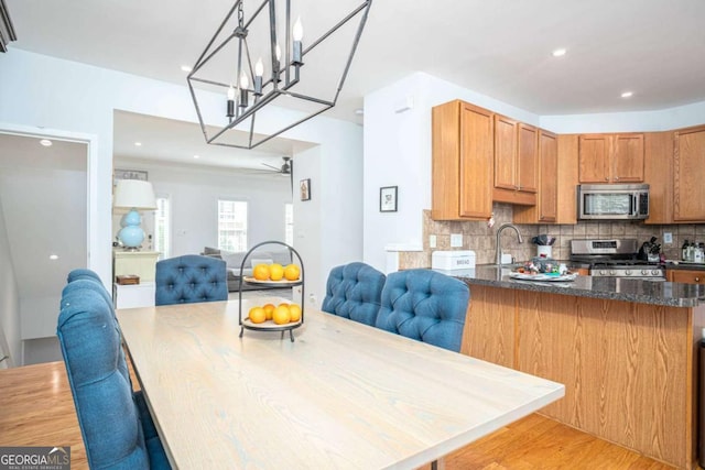 kitchen featuring open floor plan, tasteful backsplash, appliances with stainless steel finishes, and a peninsula