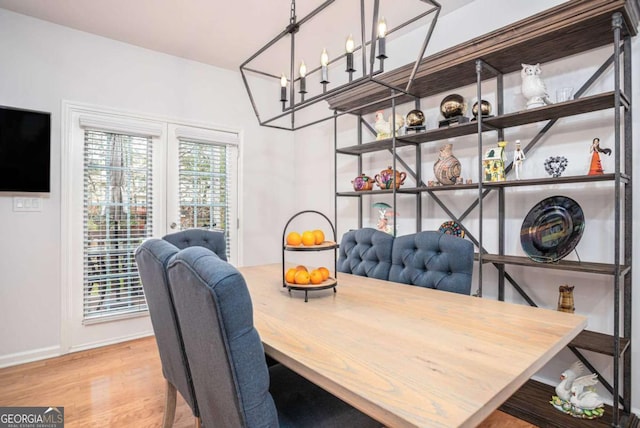 dining space with baseboards, a chandelier, and wood finished floors