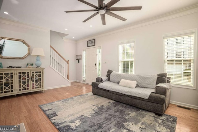 living room featuring stairway, baseboards, visible vents, ceiling fan, and wood finished floors