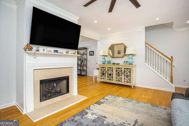 living area featuring ornamental molding, wood finished floors, stairway, and a ceiling fan