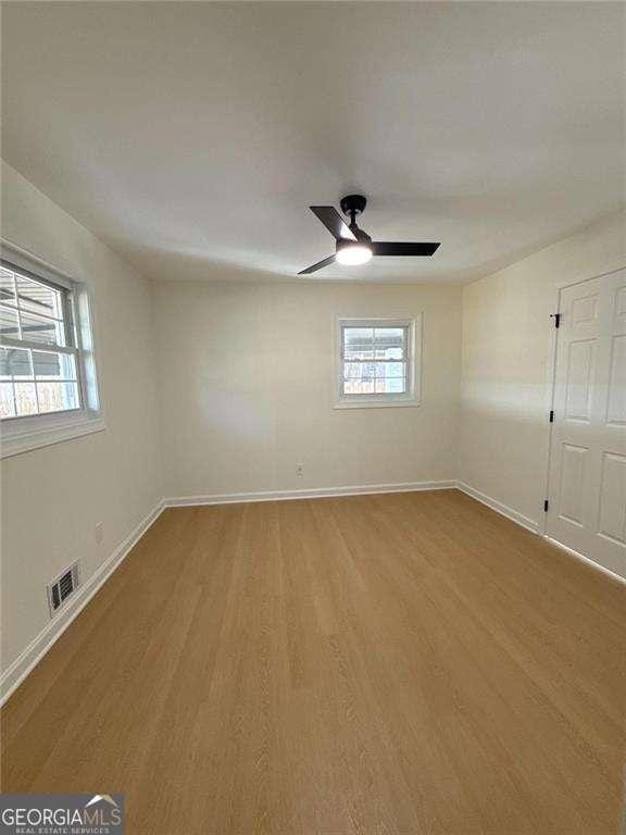 spare room with a ceiling fan, baseboards, light wood finished floors, and visible vents