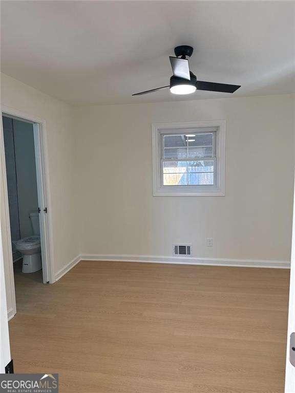spare room featuring baseboards, visible vents, light wood-style flooring, and ceiling fan