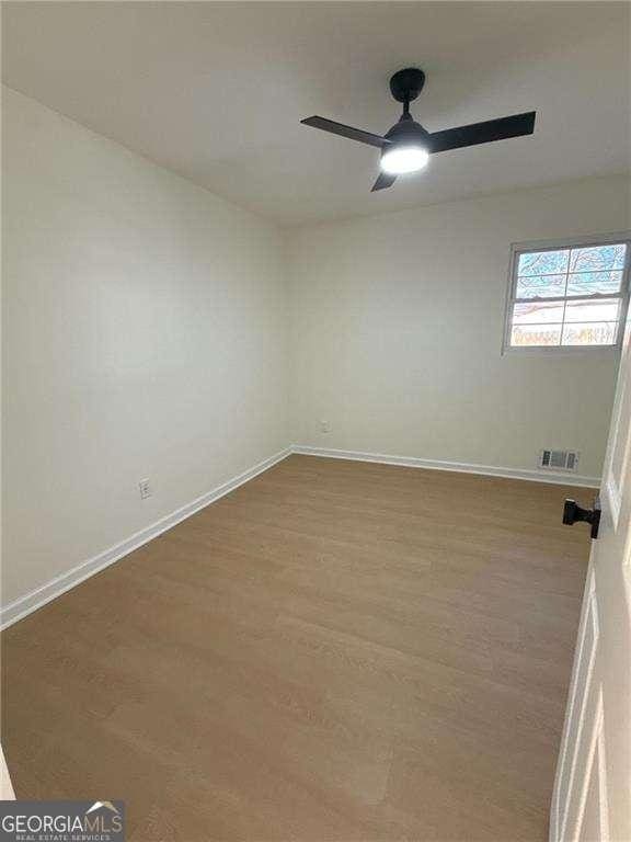 unfurnished room with baseboards, visible vents, wood finished floors, and ceiling fan