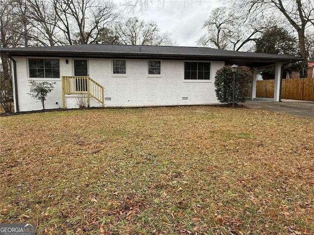 back of property featuring an attached carport, brick siding, crawl space, and a yard