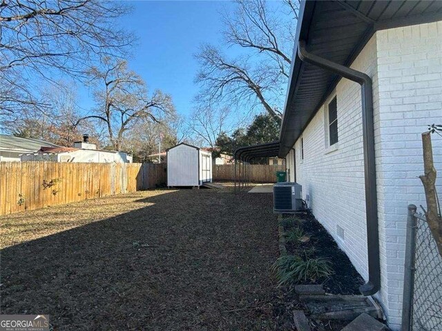 view of yard featuring an outdoor structure, a fenced backyard, a shed, and central air condition unit