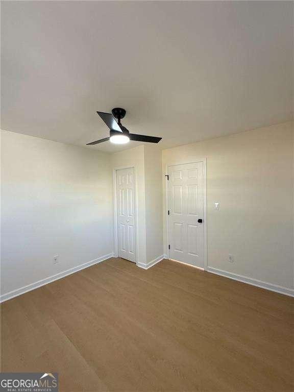 spare room with baseboards, wood finished floors, and a ceiling fan