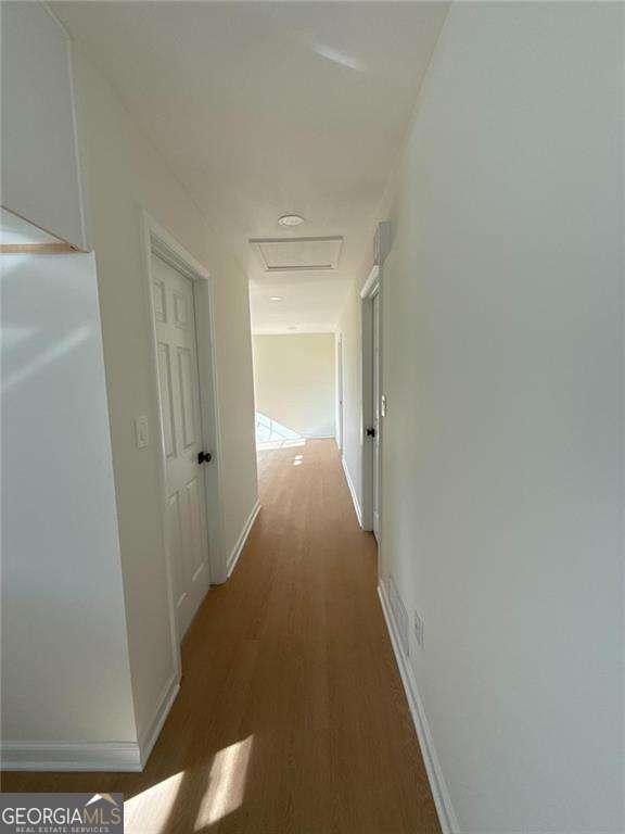 hall featuring attic access, baseboards, and wood finished floors