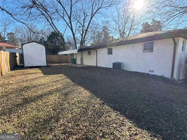 back of property featuring an outdoor structure, brick siding, a fenced backyard, a storage unit, and crawl space