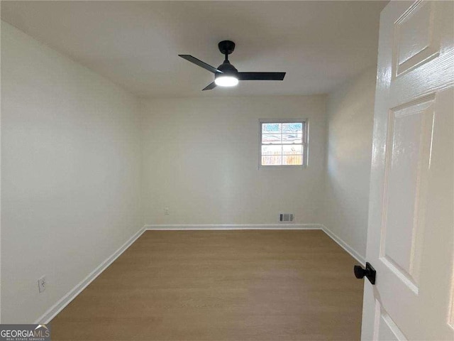 unfurnished room featuring baseboards, visible vents, wood finished floors, and a ceiling fan