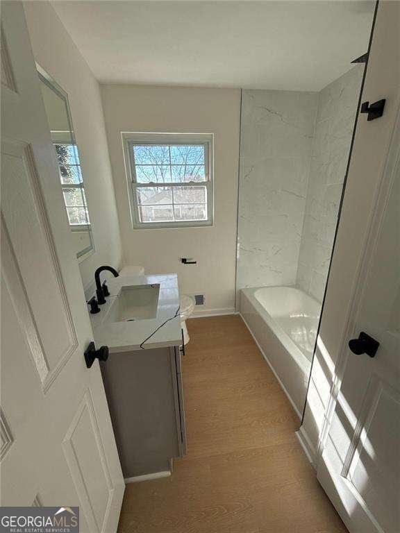 bathroom with toilet, vanity, baseboards, and wood finished floors