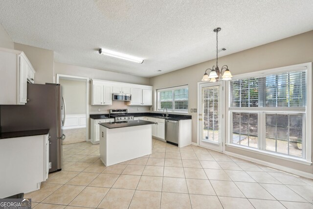 3936 Toccoa Falls Dr, Duluth, GA 30097 - kitchen with stainless steel appliances, dark countertops, a sink, a chandelier, and a textured ceiling