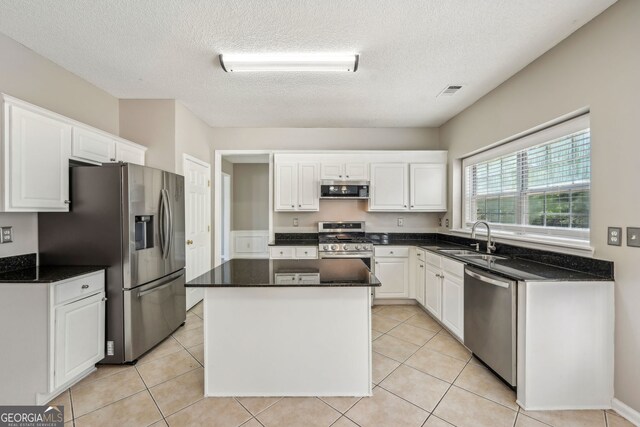 3936 Toccoa Falls Dr, Duluth, GA 30097 - kitchen featuring appliances with stainless steel finishes, a sink, white cabinetry, a kitchen island, and a textured ceiling