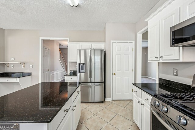 3936 Toccoa Falls Dr, Duluth, GA 30097 - kitchen with appliances with stainless steel finishes, white cabinets, a textured ceiling, dark stone counters, and light tile patterned floors