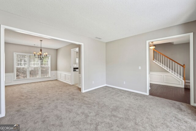 3936 Toccoa Falls Dr, Duluth, GA 30097 - spare room with a chandelier, carpet floors, stairs, wainscoting, and a textured ceiling