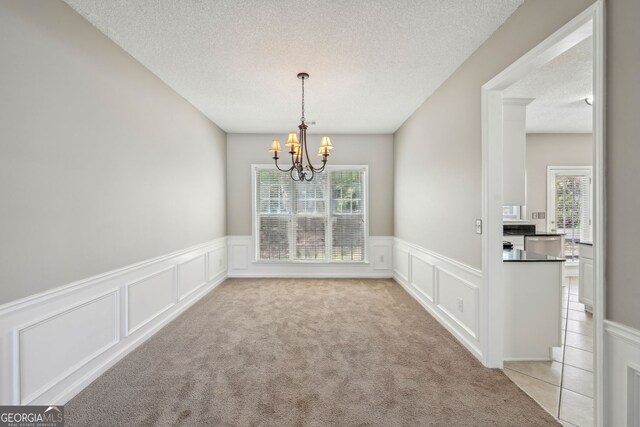 3936 Toccoa Falls Dr, Duluth, GA 30097 - unfurnished dining area with a decorative wall, a chandelier, a textured ceiling, wainscoting, and light colored carpet