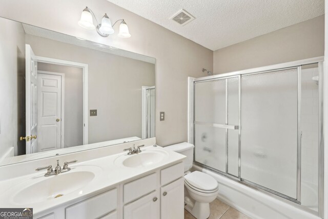 3936 Toccoa Falls Dr, Duluth, GA 30097 - full bath featuring toilet, double vanity, bath / shower combo with glass door, a textured ceiling, and tile patterned floors