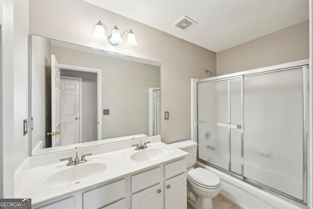 3936 Toccoa Falls Dr, Duluth, GA 30097 - bathroom with double vanity, toilet, a textured ceiling, shower / bath combination with glass door, and tile patterned flooring