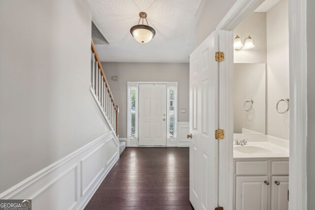 3936 Toccoa Falls Dr, Duluth, GA 30097 - entryway with a decorative wall, dark wood-style floors, wainscoting, stairs, and a textured ceiling