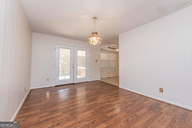 unfurnished room with a chandelier, french doors, baseboards, and wood finished floors