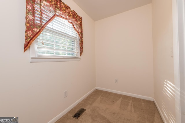spare room featuring visible vents, baseboards, and light carpet
