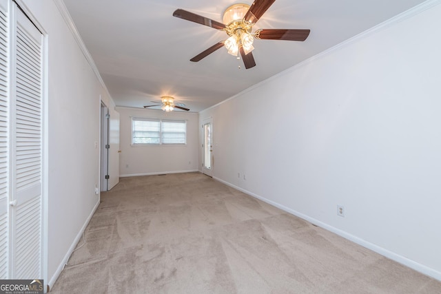 spare room with light carpet, baseboards, a ceiling fan, and ornamental molding