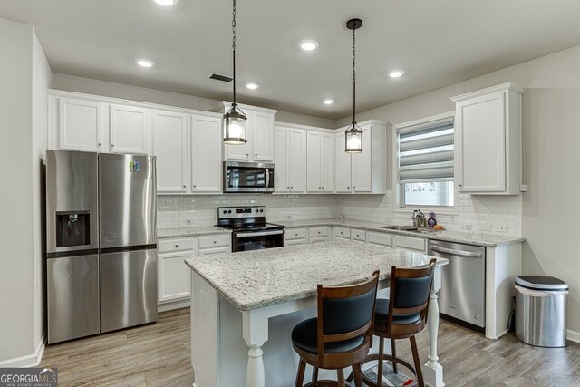 kitchen featuring visible vents, white cabinets, light wood-style flooring, and stainless steel appliances