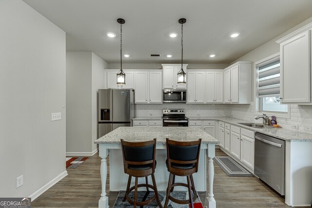 kitchen with dark wood finished floors, white cabinetry, backsplash, and appliances with stainless steel finishes
