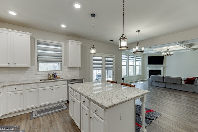 kitchen with coffered ceiling, backsplash, a kitchen island, wood finished floors, and recessed lighting