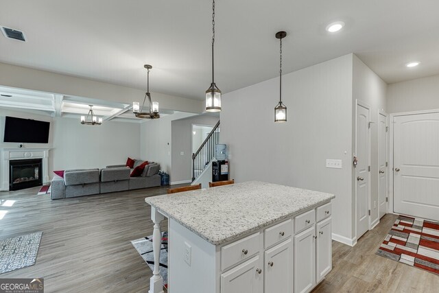 kitchen with white cabinetry, hanging light fixtures, a center island, light wood-type flooring, and visible vents
