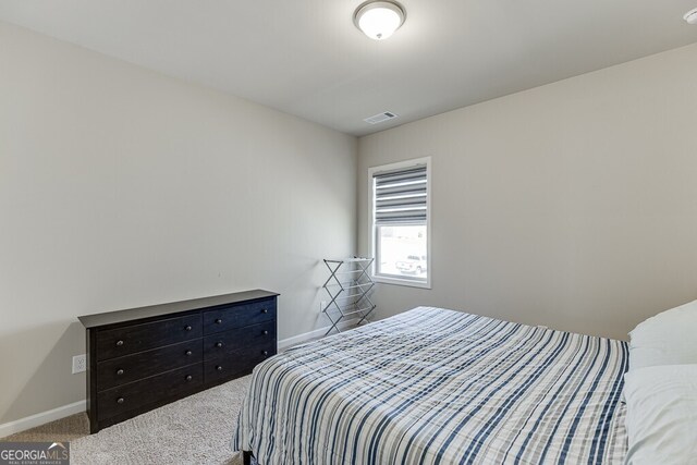 bedroom with baseboards, visible vents, and carpet