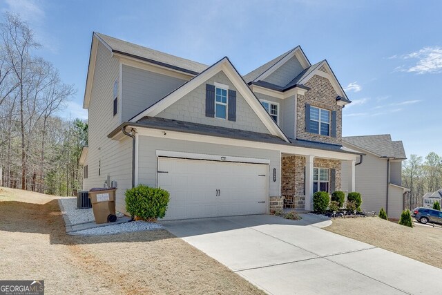 craftsman-style house featuring an attached garage, central air condition unit, and concrete driveway