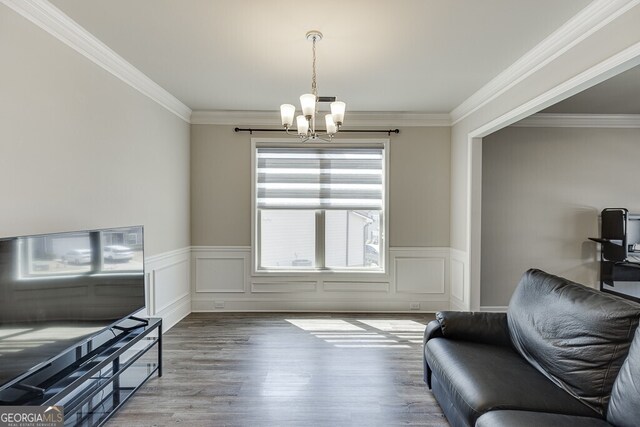 sitting room featuring crown molding, wood finished floors, a notable chandelier, and wainscoting