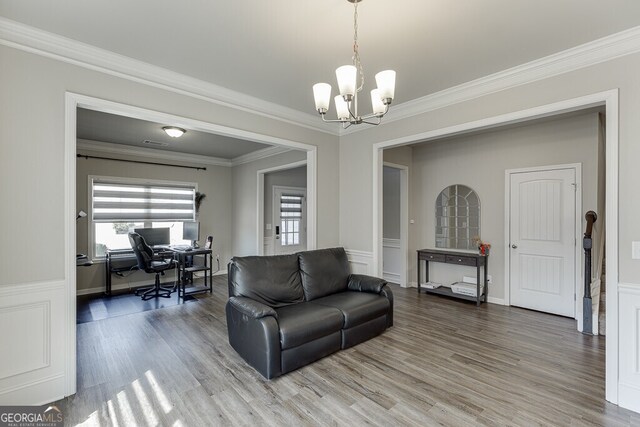 living room featuring a notable chandelier, wood finished floors, baseboards, visible vents, and ornamental molding