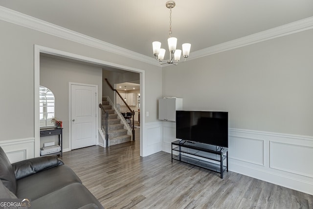 living area featuring wood finished floors, a chandelier, stairway, and crown molding