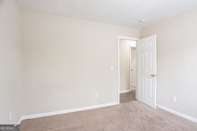 carpeted empty room with baseboards and a textured ceiling