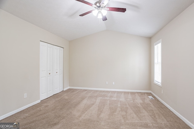 unfurnished bedroom featuring a closet, lofted ceiling, baseboards, visible vents, and carpet