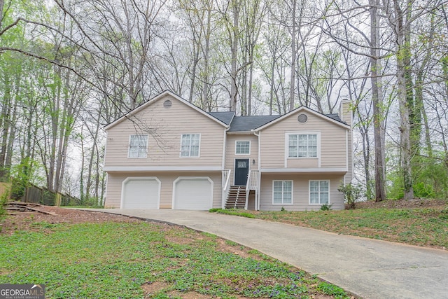 split foyer home featuring concrete driveway, a garage, and a chimney